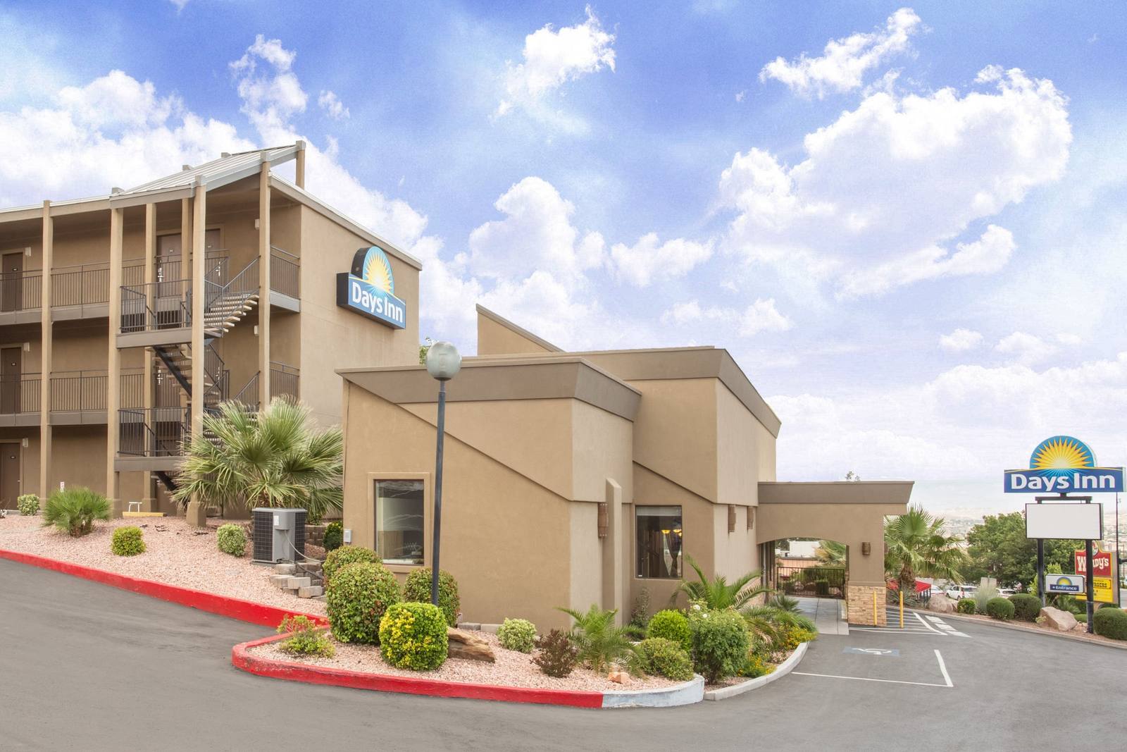 Days Inn by Wyndham St. George exterior with palm trees and desert landscaping