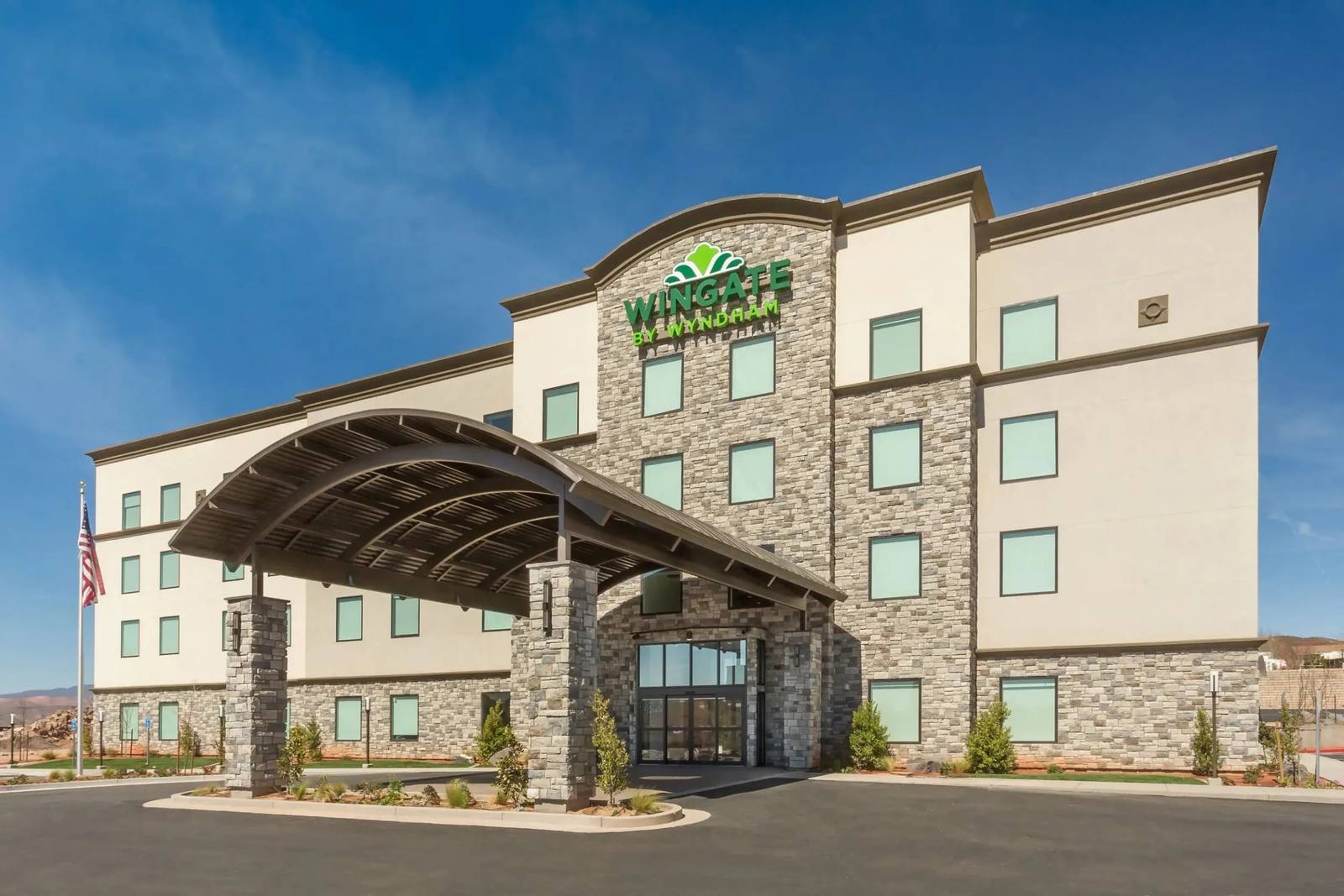 Wingate by Wyndham hotel with a stone-clad entrance canopy under a blue sky